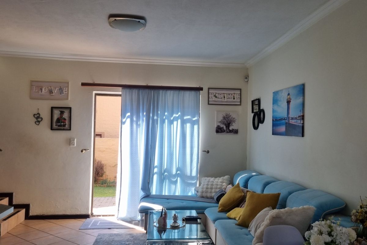 A living room featuring tiled flooring, a staircase, and a sliding door providing access to the exterior.