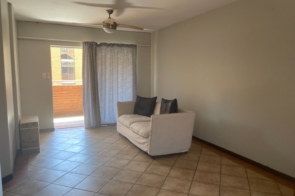 A living room featuring tiled flooring, a ceiling fan, and direct access to an outdoor balcony area.