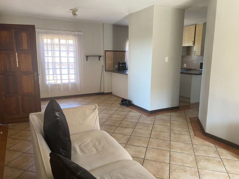 Open plan living area featuring tiled flooring and a functional kitchen with built-in cabinetry and countertops.