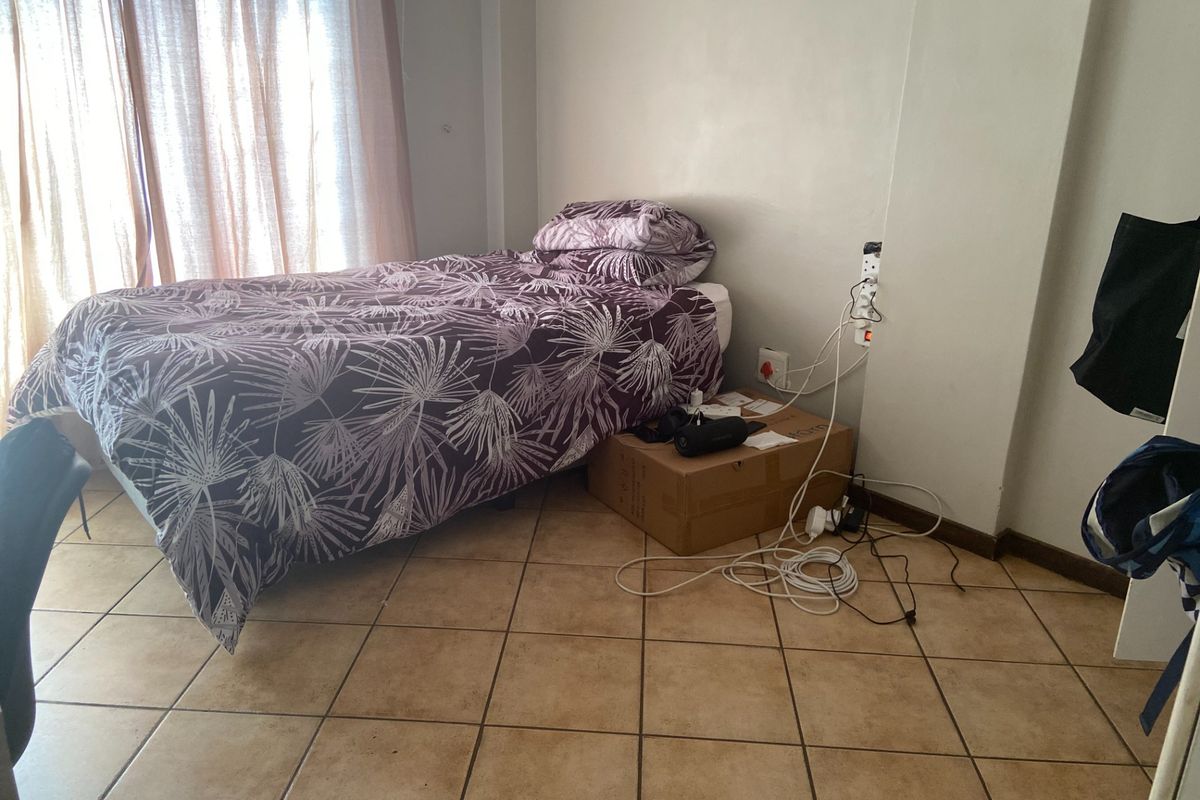 A bedroom featuring tiled flooring and standard electrical power points, providing a functional space with natural light from the window.