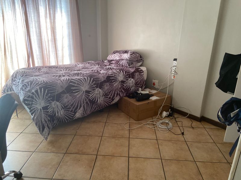 A bedroom featuring tiled flooring and standard electrical power points, providing a functional space with natural light from the window.