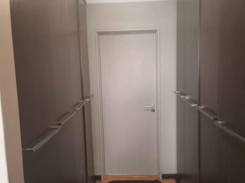 A functional hallway featuring extensive built-in floor-to-ceiling cabinetry providing ample storage space, finished with laminate flooring and neutral wall tones.