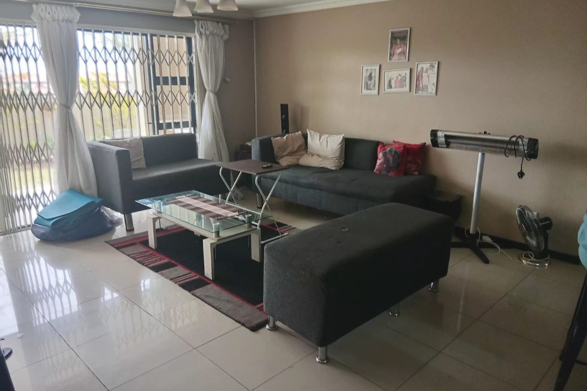 A living room featuring tiled flooring, a sliding glass door with a security gate, and neutral wall finishes.
