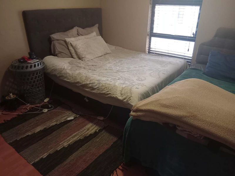 A bedroom featuring a window with fitted venetian blinds and laminate flooring.