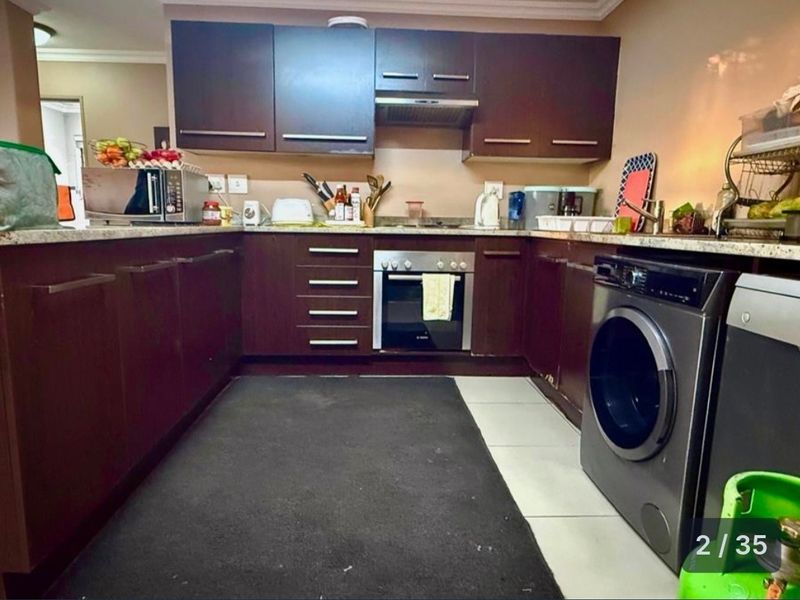 A functional kitchen featuring dark wood cabinetry, granite countertops, a built-in oven, and an integrated extractor fan with tiled flooring.
