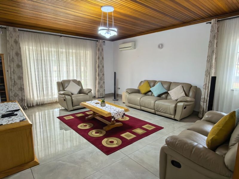 Spacious living room featuring polished tiled flooring, a warm timber-clad ceiling, and large sliding glass doors that provide ample natural light.