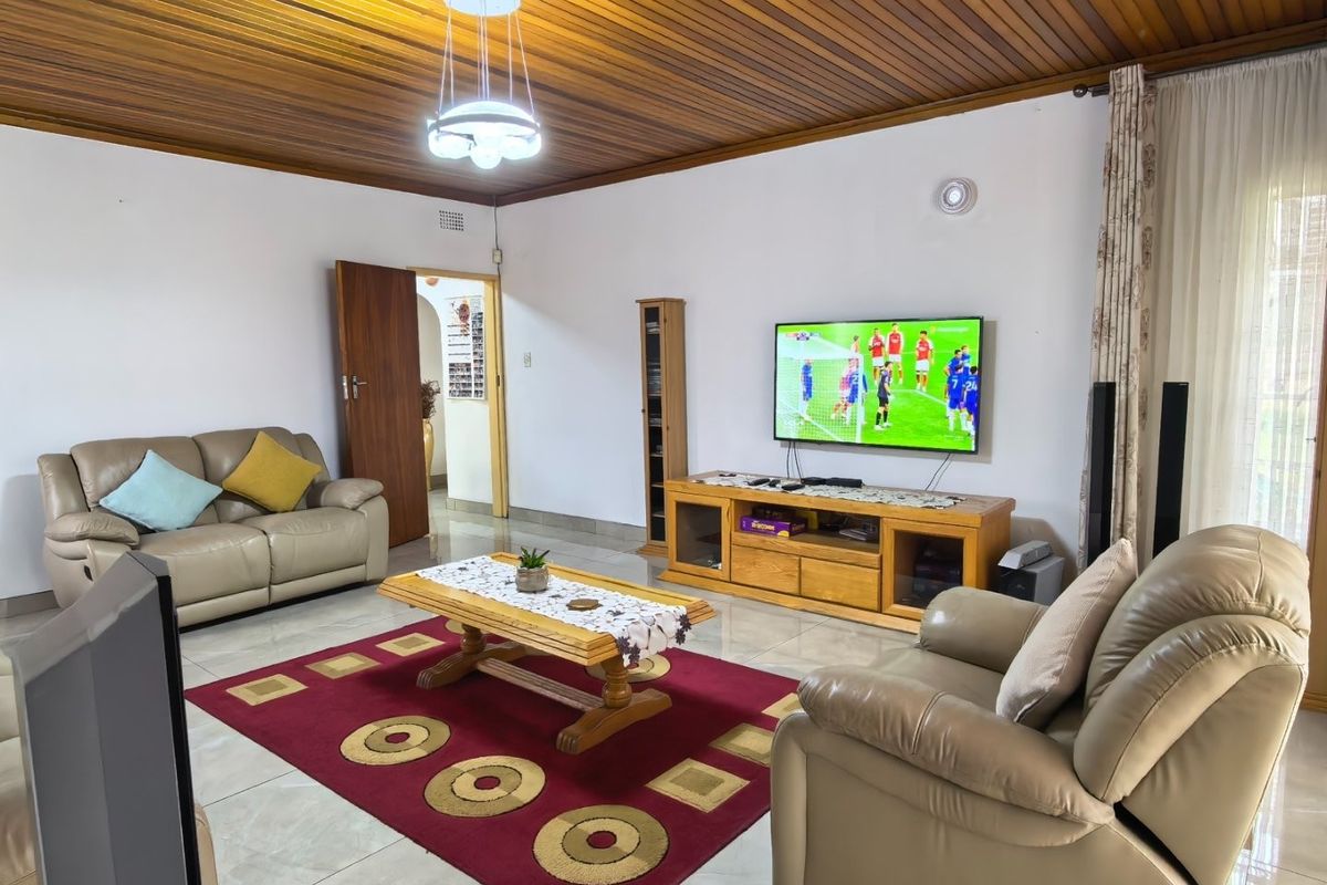Spacious living room featuring a warm timber tongue and groove ceiling, polished tiled flooring, and direct access to outdoor areas via sliding glass doors.