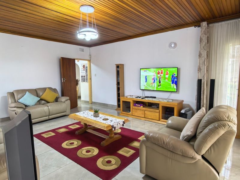 Spacious living room featuring a warm timber tongue and groove ceiling, polished tiled flooring, and direct access to outdoor areas via sliding glass doors.