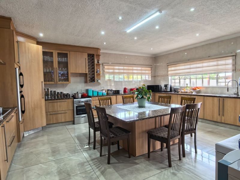 Spacious kitchen featuring light wood cabinetry, granite countertops, a central island, and modern tiled flooring with ample natural light.