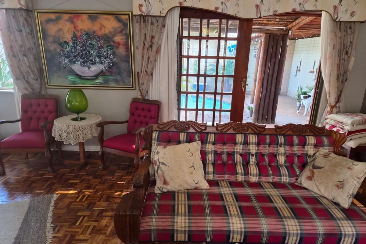 A living room featuring traditional parquet flooring and a wooden framed glass door providing direct access to an outdoor patio and pool area.