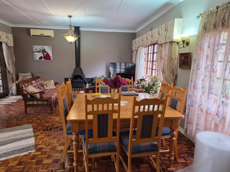 Spacious open-plan living and dining area featuring classic parquet flooring, a prominent freestanding fireplace, and split-system air conditioning.