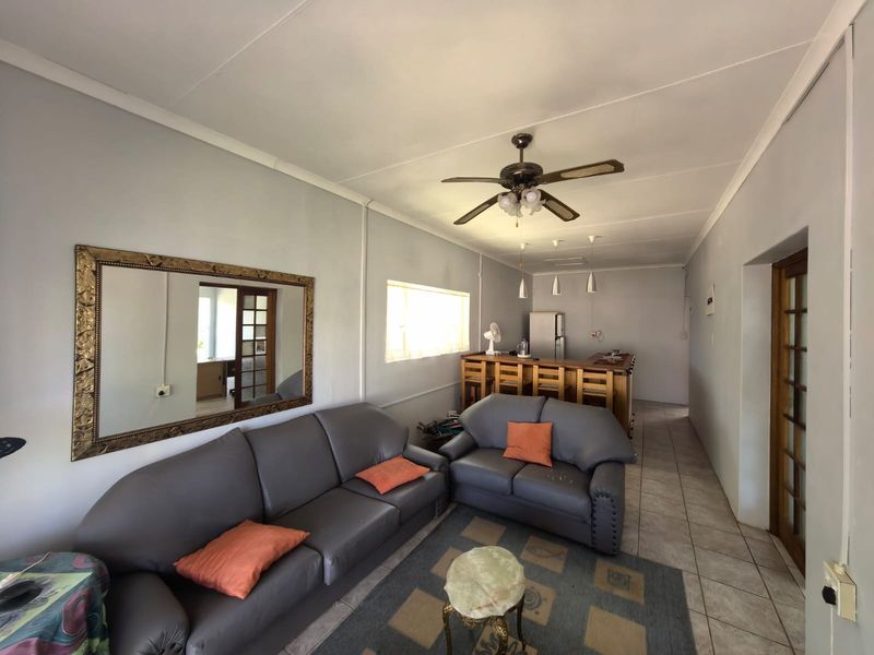 Open plan living area featuring tiled flooring, a breakfast bar, and a ceiling fan, offering a functional layout for casual dining and relaxation.