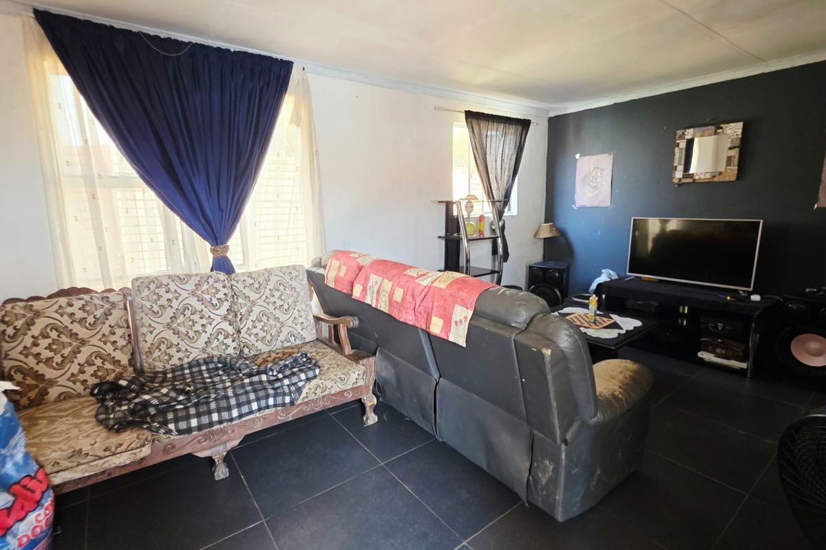 A living room featuring dark tiled flooring and a dark accent wall, offering a blank canvas for potential interior updates and modernization.