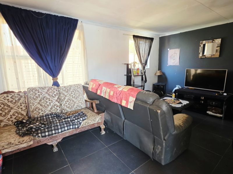 A living room featuring dark tiled flooring and a dark accent wall, offering a blank canvas for potential interior updates and modernization.