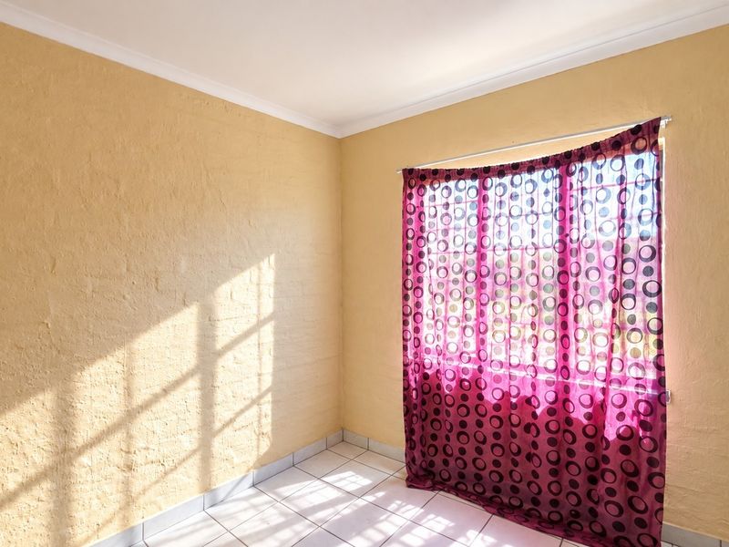 A bright, empty bedroom featuring tiled flooring and textured walls, ready for personalization.