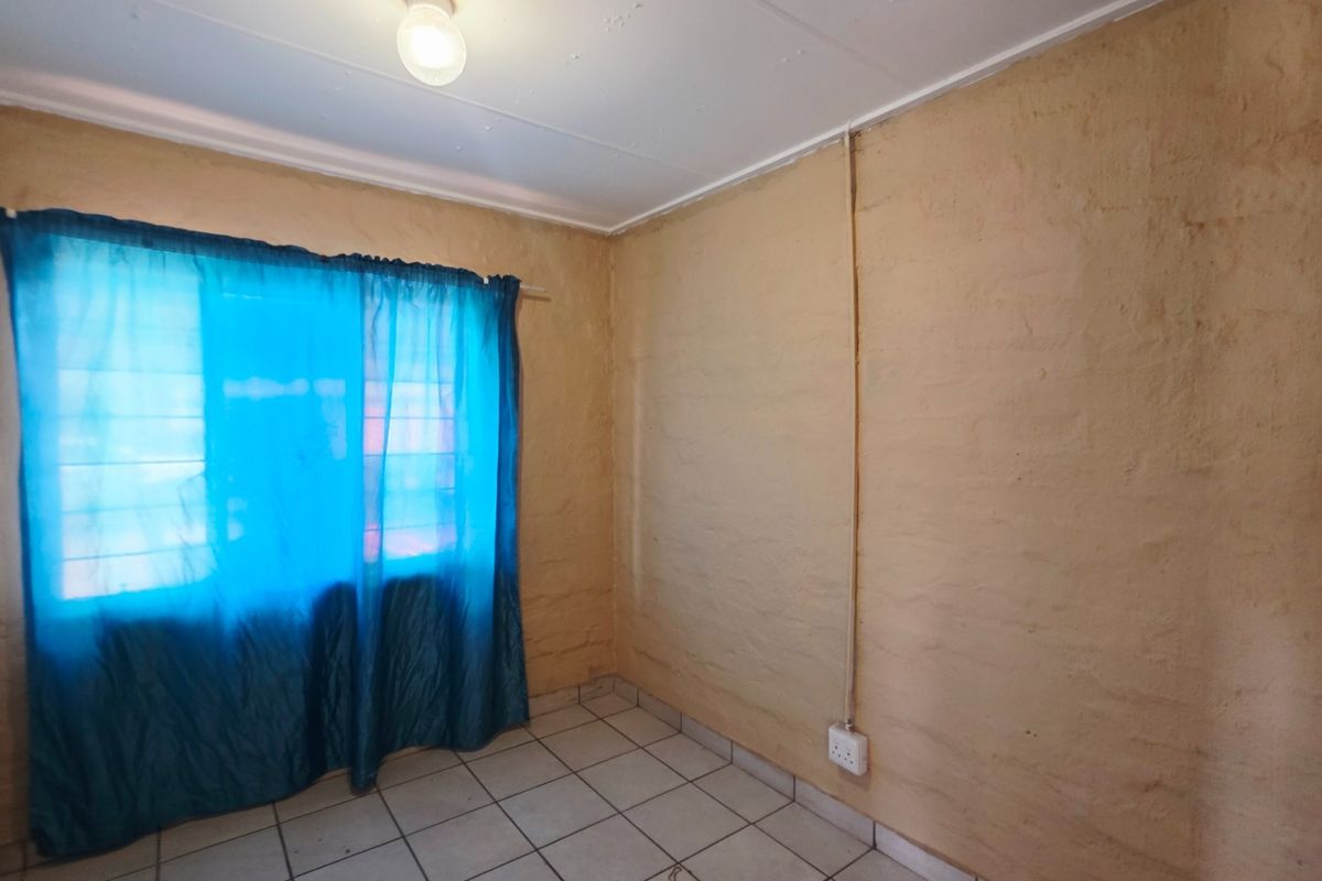 A vacant bedroom featuring tiled flooring, built-in cupboards, and textured wall finishes with surface-mounted electrical conduit.