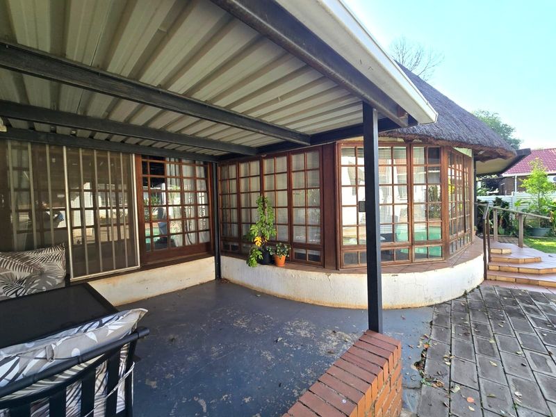 Covered patio area featuring a corrugated metal roof, timber-framed windows, and brick accents, providing a functional outdoor space for relaxation.