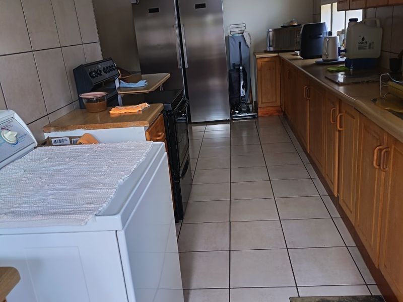 A functional kitchen featuring wooden cabinetry, tiled flooring, and a tiled splashback, offering a practical layout for daily use.