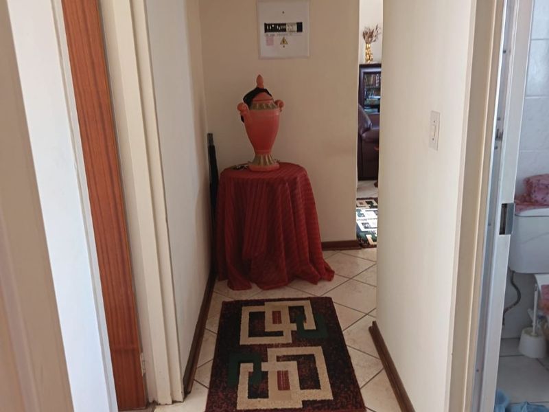 A functional hallway featuring tiled flooring and access to adjacent rooms, including a view into a bathroom and living area.