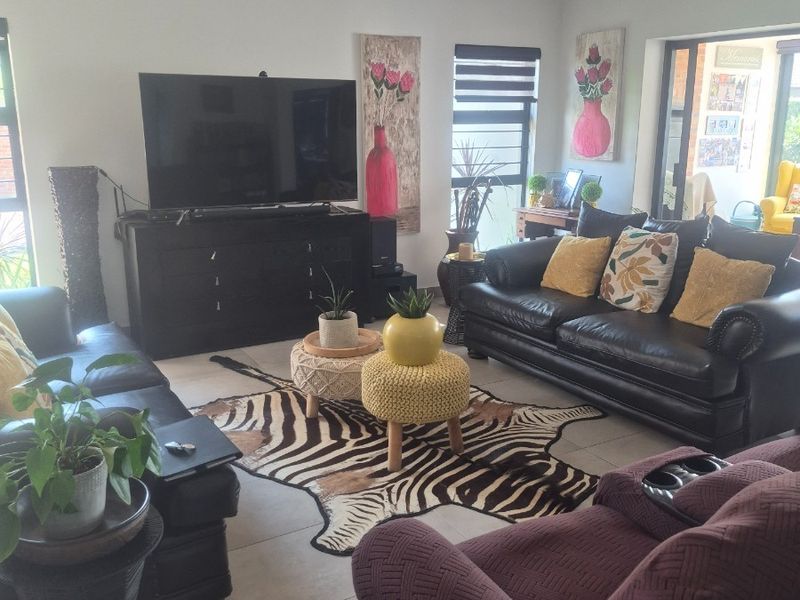 A comfortable living room featuring tiled flooring, recessed downlighting, and a large sliding glass door providing access to the outdoor area.