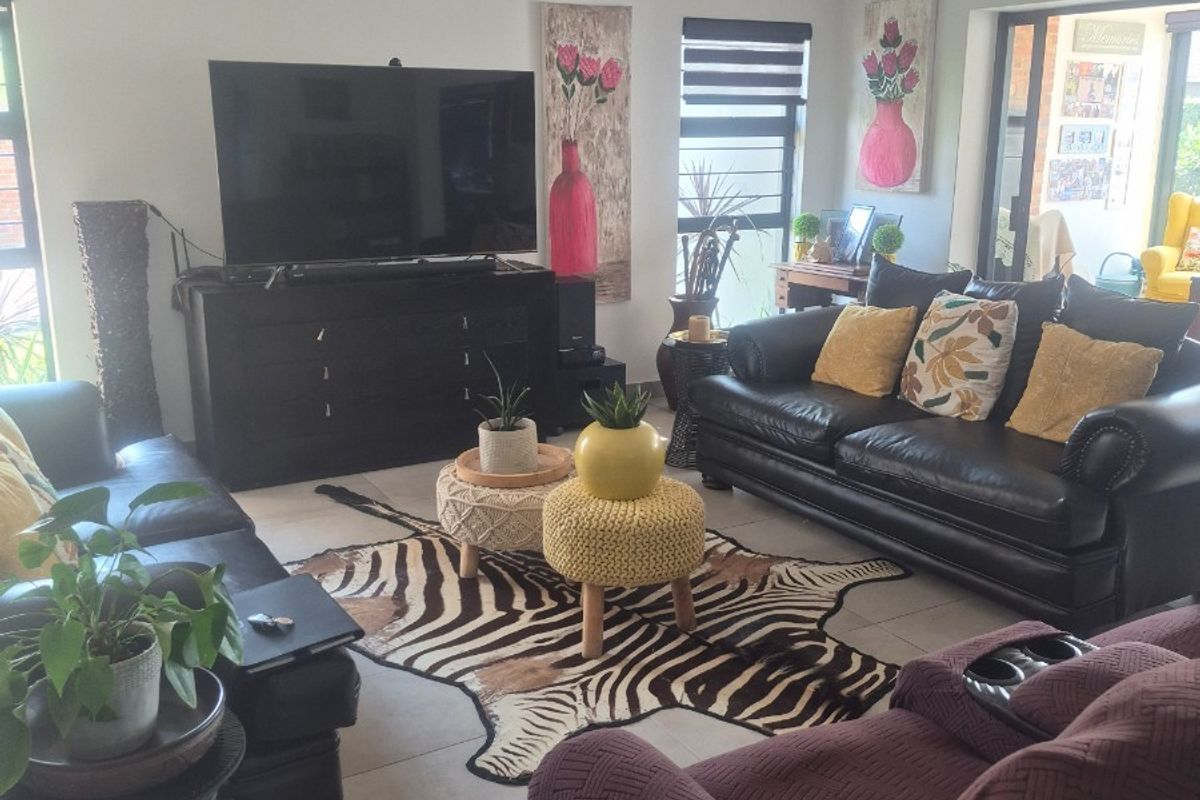 A comfortable living room featuring tiled flooring, recessed downlighting, and a large sliding glass door providing access to the outdoor area.