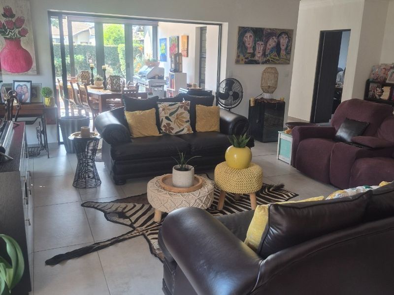Spacious living room featuring large sliding glass doors that open to an outdoor patio area, complemented by neutral tiled flooring and recessed lighting.