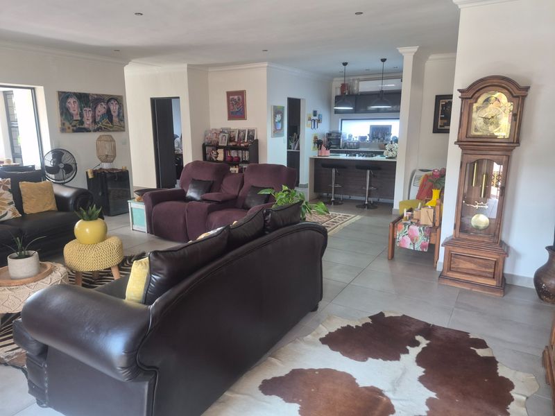 Spacious open-plan living area featuring tiled floors, recessed lighting, and a functional kitchen with a central island and built-in cabinetry.