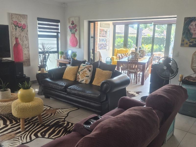Spacious open-plan living area featuring tiled floors, recessed lighting, and large sliding glass doors that provide seamless access to the outdoor patio.