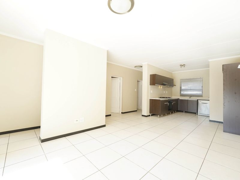 Spacious open-plan living area featuring tiled floors and a functional kitchen with built-in cabinetry, oven, and hob.