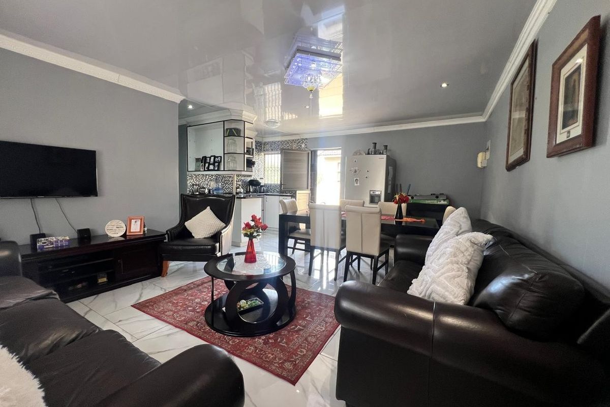 Spacious open-plan living and dining area featuring high-gloss reflective ceilings, modern marble-look floor tiles, and integrated kitchen cabinetry.