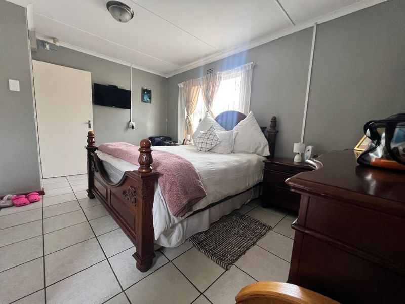 A bedroom featuring tiled flooring and neutral wall finishes, with visible surface-mounted electrical conduit and a standard window.
