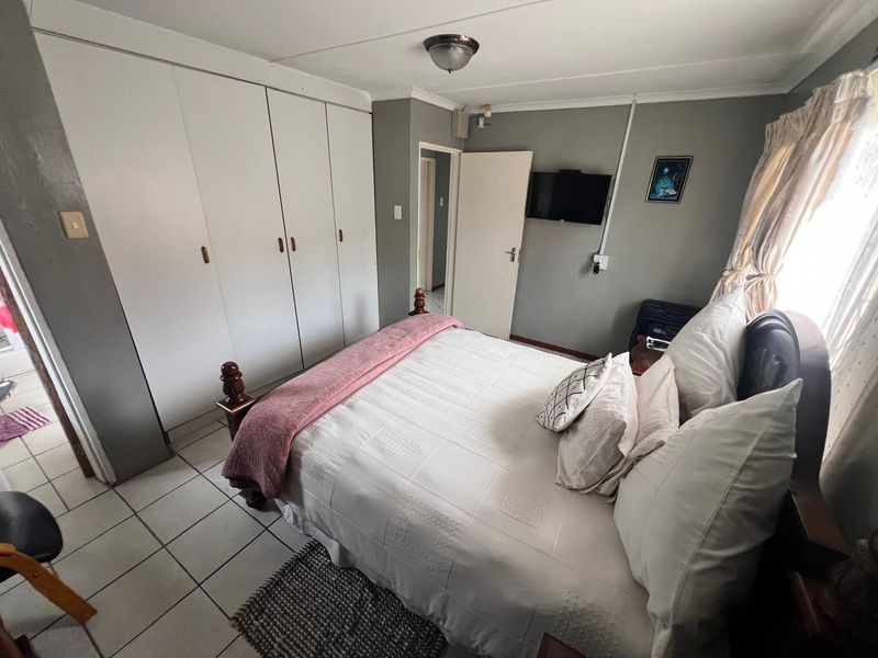 A functional bedroom featuring built-in cupboards, tiled flooring, and neutral wall finishes, providing a practical and comfortable living space.