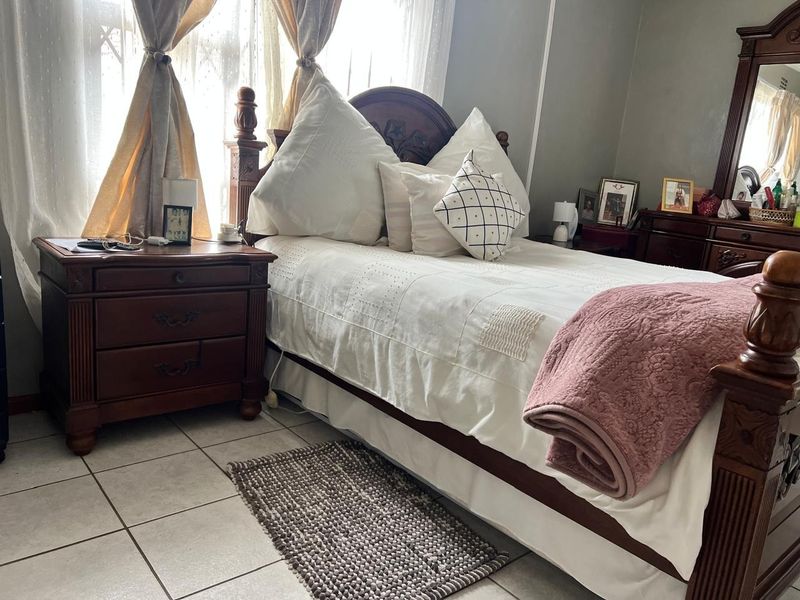 A bedroom featuring tiled flooring and natural light through window treatments.
