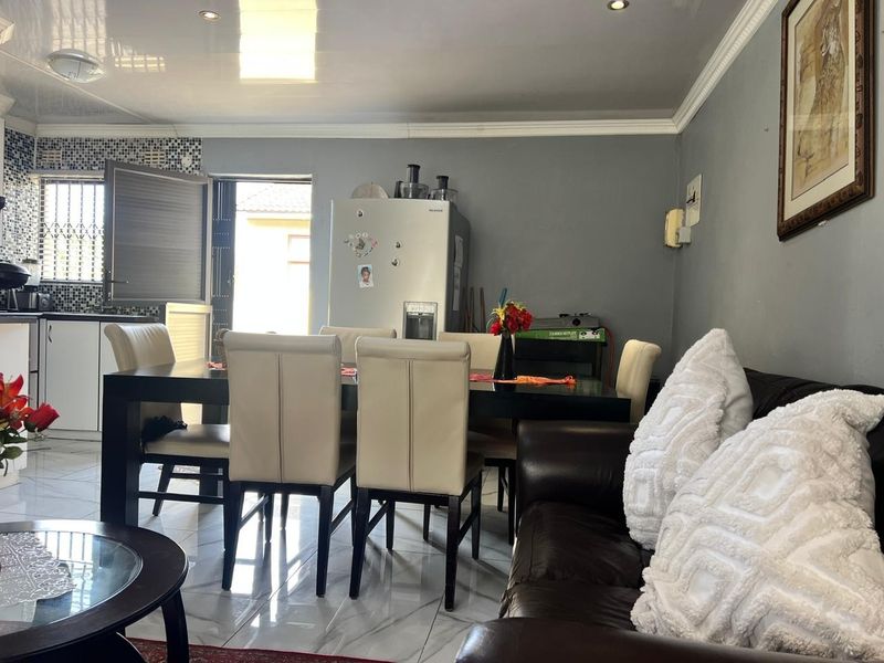 Open-plan living and dining area featuring tiled floors, recessed lighting, and an adjacent kitchen space with mosaic backsplash and direct outdoor access.