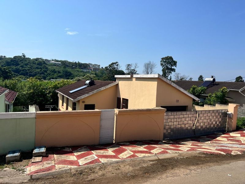 Front exterior view of a residential house featuring a solar water heater, boundary wall, and metal gate access from the street.