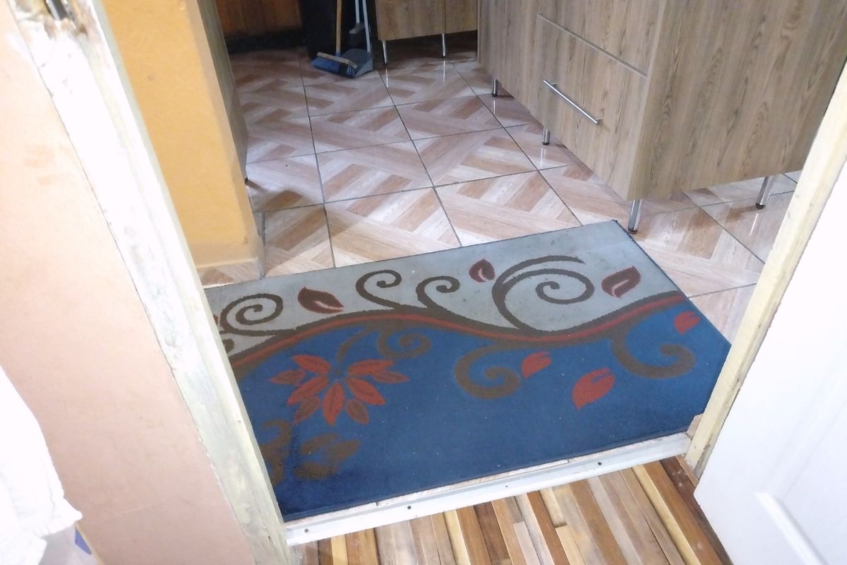 A view through a doorway into a kitchen area featuring tiled flooring and built-in cabinetry.