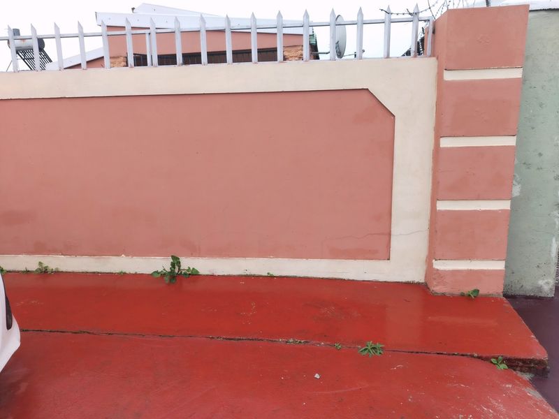 A view of the property's perimeter wall featuring metal security spikes and a painted concrete driveway.