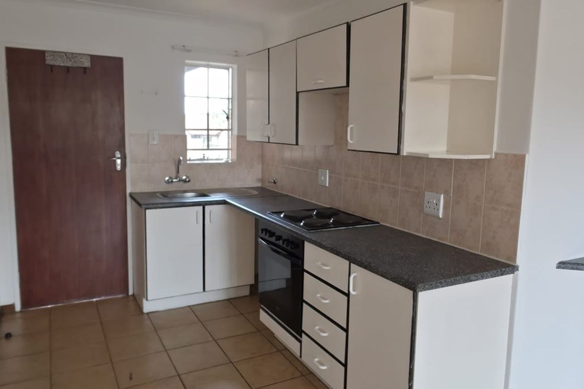 A functional kitchen featuring built-in cabinetry, laminate countertops, an electric hob, and an oven, with tiled flooring and backsplash.