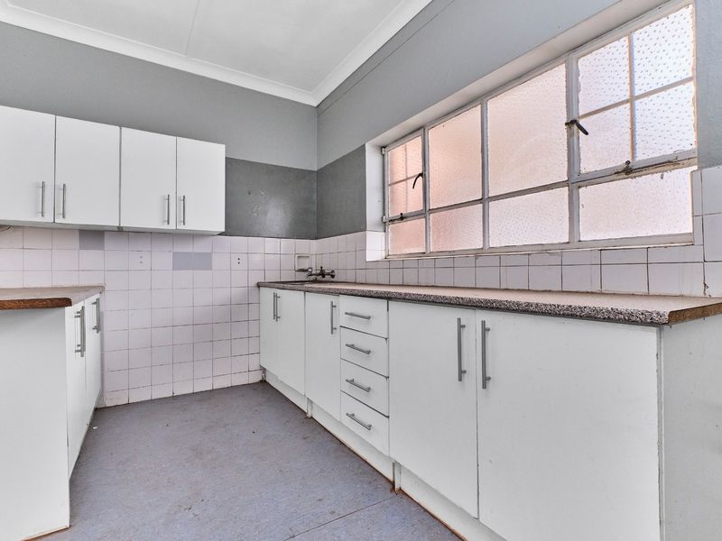 An empty kitchen featuring white built-in cabinetry, laminate countertops, and a tiled backsplash, offering a blank canvas for renovation.