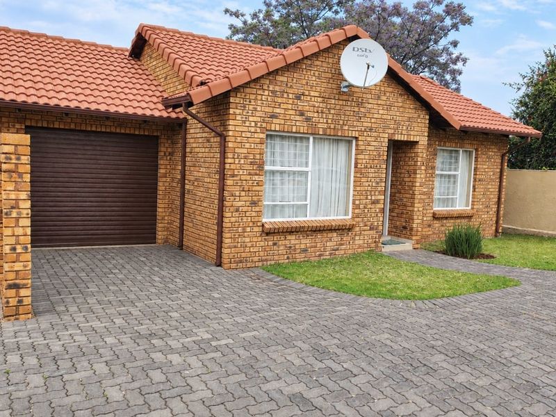 Front elevation of a face brick house featuring a tiled roof, paved driveway, and an integrated single garage.