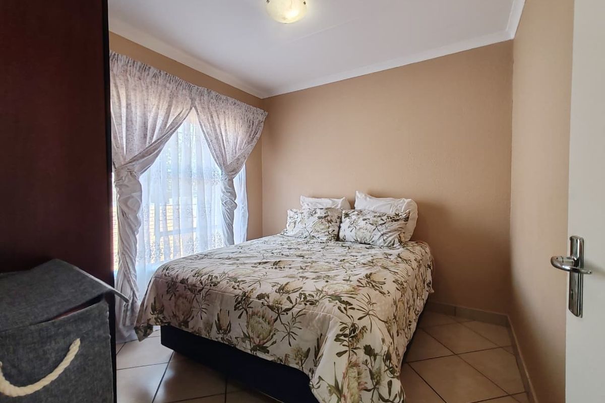 A functional bedroom featuring tiled flooring, neutral wall tones, and a coved ceiling, providing a comfortable and well-maintained living space.