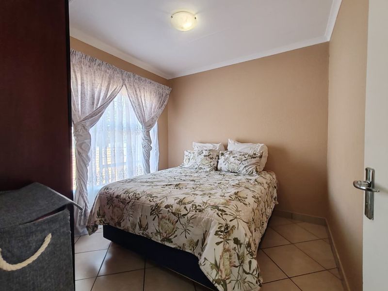 A functional bedroom featuring tiled flooring, neutral wall tones, and a coved ceiling, providing a comfortable and well-maintained living space.