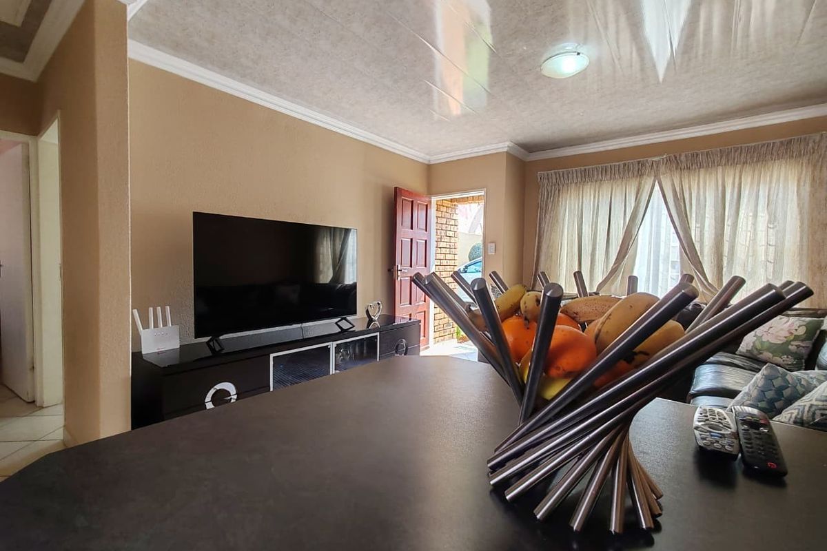 A living room area featuring a coved ceiling, tiled ceiling panels, and direct access to the exterior through a timber door.