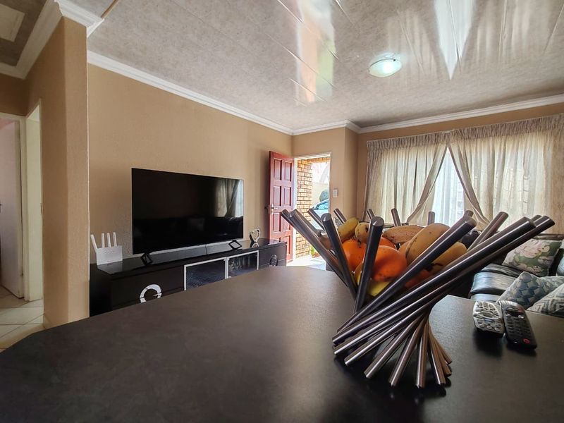 A living room area featuring a coved ceiling, tiled ceiling panels, and direct access to the exterior through a timber door.
