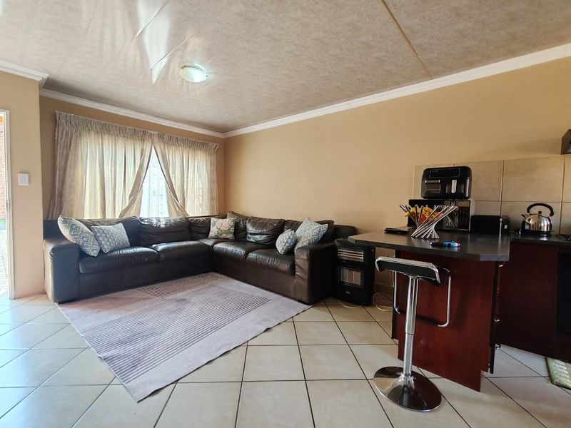 Open plan living area featuring tiled flooring, a breakfast bar, and coved ceilings, creating a functional combined space.