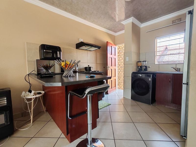 A functional kitchen featuring dark wood cabinetry, a central island, tiled flooring, and a tiled backsplash, providing a practical workspace for daily cooking.