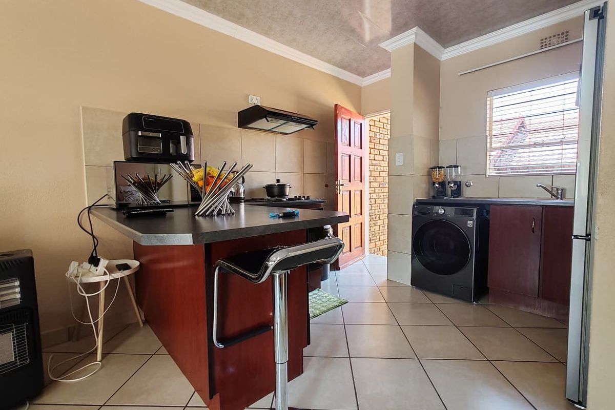 A functional kitchen featuring dark wood cabinetry, a central island, tiled flooring, and a tiled backsplash, providing a practical workspace for daily cooking.