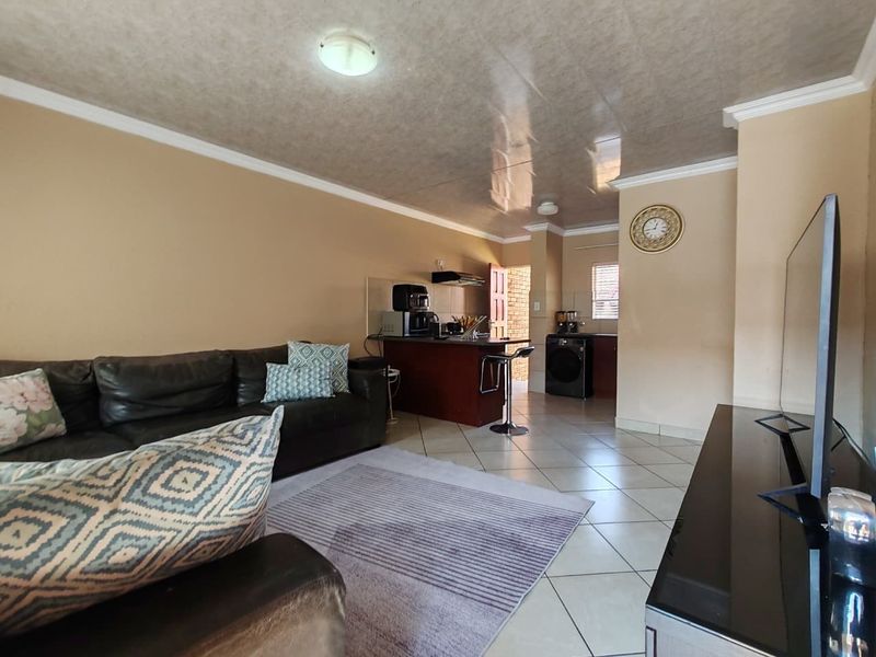 An open-plan living and kitchen area featuring tiled flooring, a breakfast counter, and a functional kitchen layout with built-in cabinetry.