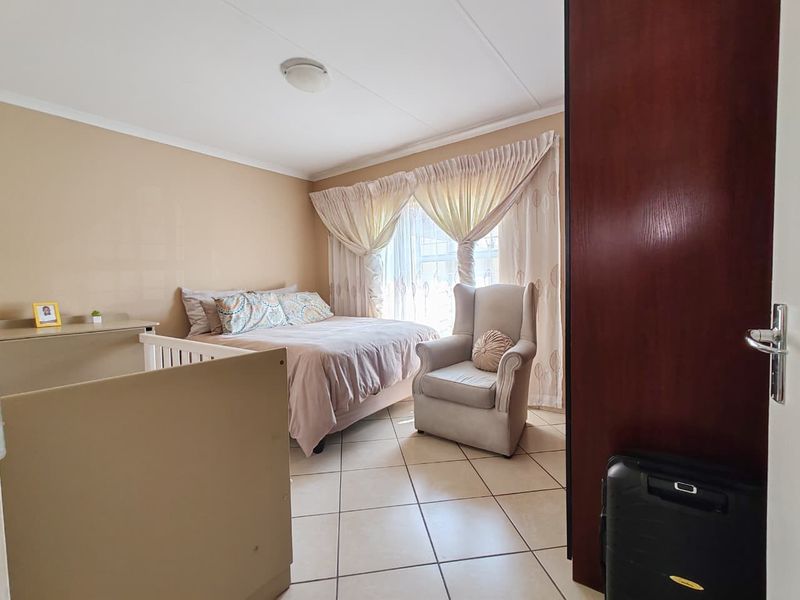 A functional bedroom featuring tiled flooring and a built-in cupboard, offering a neutral canvas for potential interior updates.