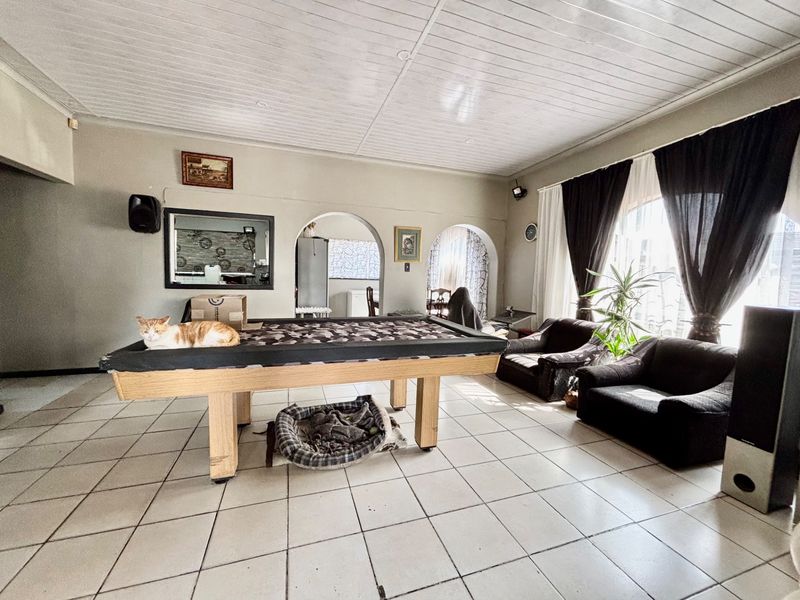 Spacious living area featuring tiled flooring, tongue and groove ceiling, and distinctive archway transitions to adjacent rooms.